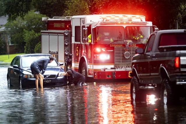 People attach a towline to a stranded vehicle on a flooded street after heavy rain from Tropical Storm Debby, Monday, August 5, 2024, in Savannah, Ga. (Photo by Stephen B. Morton/AP Photo)