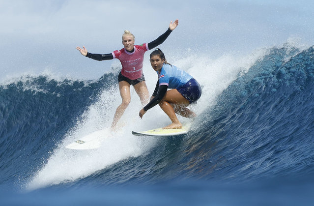 Tatiana Weston-Webb, of Brazil, left, reacts as Brisa Hennessy, of Costa Rica, drops in on her during the semifinal round of the surfing competition at the 2024 Summer Olympics, Monday, August 5, 2024, in Teahupo'o, Tahiti. (Photo by Ben Thouard/Pool Photo via AP Photo)