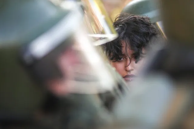 A detained demonstrator is seen among members of the security forces during a protest against Chile's government in Santiago, Chile on December 17, 2019. (Photo by Ricardo Moraes/Reuters)