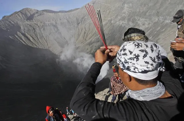 A worshipper prays at the crater of Mount Bromo during Yadnya Kasada festival in Probolinggo, East Java, Indonesia, Saturday, August 1, 2015. Every year people gather for the annual festival where offerings of rice, fruit, vegetables, livestock or money are made to Hindu gods at the active volcano to ask for blessings and assure a bountiful harvest. (Photo by AP Photo/Trisnadi)