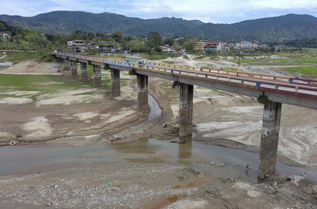 Aerial view of a bridge in the El Peñol-Guatape Reservoir in Guatape, department of Antioquia, 62 km east of Medellin, Colombia, taken on March 12, 2024. The Institute of Hydrology, Meteorology, and Environmental Studies (Ideam) warned in January 2024 that Colombians would continue to suffer the effects of the El Niño phenomenon until at least April of this year, followed by a neutral phase that would last until June. (Photo by Jaime Saldarriaga/AFP Photo) 