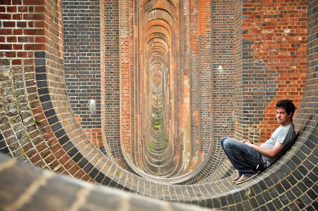 Mike poses against a curved wall which looks like an optical illusion. (Photo by Mike Deere/Caters News)