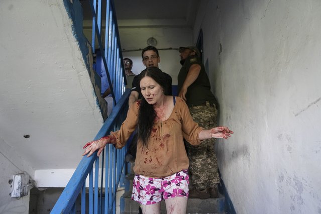 An injured woman runs down a staircase after a Russian rocket attack on residential neighborhood in Pervomaiskyi, Kharkiv region, Ukraine, Tuesday, July 4, 2023. (Photo by Oleksandr Magula/AP Photo)