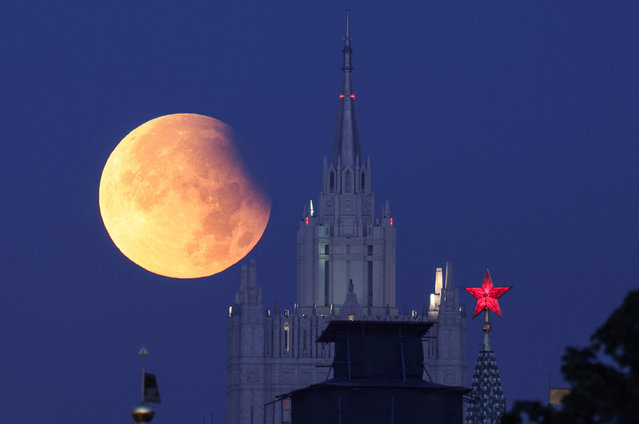 Partial lunar eclipse is seen with a star atop of the tower of the Kremlin and Russia's Foreign Ministry headquarters building in the foreground, in Moscow, Russia on September 18, 2024. (Photo by Marina Lystseva/Reuters)