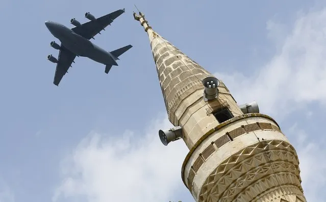 A U.S. Air Force Boeing C-17A Globemaster III large transport aircraft flies over a minaret after taking off from Incirlik air base in Adana, Turkey, August 12, 2015. (Photo by Murad Sezer/Reuters)