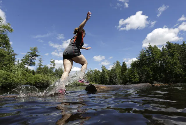 In this July 10, 2014 photo, Emily Eidman, of New City, N.Y., performs the boom run on Lower St. Regis Lake at the Adirondack Woodsmen's School at Paul Smith's College in Paul Smiths, N.Y. Eighteen young students in matching gray sports shirts took part recently in a weeklong crash course on old-school lumberjack skills such as sawing, chopping, ax throwing, log boom running and pole climbing. (Photo by Mike Groll/AP Photo)