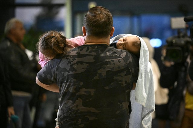 A man carries two children after arriving at Sofia airport on a Bulgarian government evacuation flight from Lebanon, in Sofia on September 30, 2024. (Photo by Nikolay Doychinov/AFP Photo)