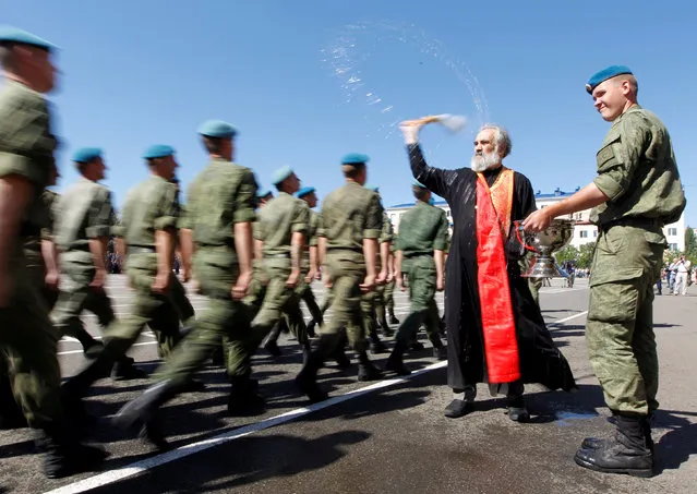 An Orthodox priest blesses Russian paratroopers marching during Paratroopers' Day celebrations, the annual holiday of Russian Airborne Troops, at their military unit in the southern city of Stavropol,  Russia, August 2, 2017. (Photo by Eduard Korniyenko/Reuters)