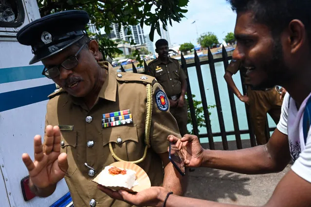 Demonstrators distribute auspicious milk rice as a part of celebration after the resignation of ousted Sri Lanka's President Gotabaya Rajapaksa at the Presidential Secretariat in Colombo on July 15, 2022. The resignation of Sri Lanka's president has been accepted, the crisis-hit country's parliamentary speaker announced Friday, after he fled the country earlier this week, prompting relief among protesters camped outside his former offices. (Photo by Arun Sankar/AFP Photo)