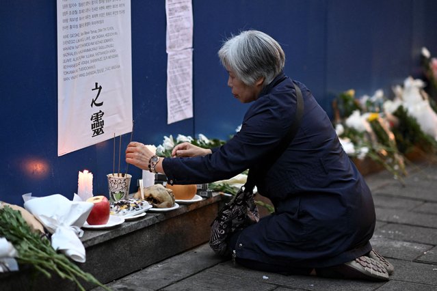 A woman burns incense to pay her respects on a wall in an alleyway in Seoul on October 29, 2024, which was the site of the tragic crowd crush that killed 159 people during Halloween celebrations, in Seoul’s popular Itaewon nightlife area two years ago. (Photo by Shin Yong-ju/AFP Photo)