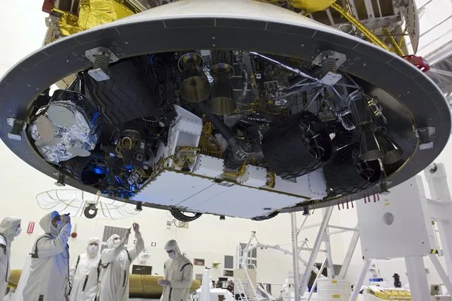 In the Payload Hazardous Servicing Facility at NASA's Kennedy Space Center in Florida, technicians inspect beneath NASA's Mars Science Laboratory (MSL) mission aeroshell, (containing the rover Curiosity), which has been mated to the cruise stage. (Photo by Glenn Benson/NASA)