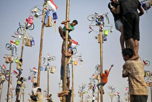 Participants struggle to reach the prizes during a greased-pole climbing competition held as a part of the independence day celebrations in Jakarta, Indonesia, Sunday, August 17, 2014. Indonesia is celebrating its 69th independence from the Dutch colonial rule. (Photo by Dita Alangkara/AP Photo)