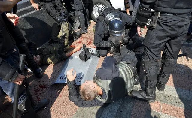 Ukrainian police and national guard officers assist injured colleagues outside the parliament building in Kiev, Ukraine, August 31, 2015. (Photo by Reuters/Stringer)