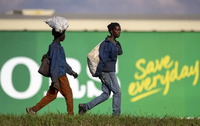 Men carrying recycling material walk in the industrial area in Daveyton, east of Johannesburg, South Africa, Tuesday, March 24, 2020, a day after it was announced that South Africa will go into a nationwide lockdown for 21 days from Thursday to fight the spread of the new coronavirus. The highly contagious COVID-19 coronavirus can cause mild symptoms, but for some it can cause severe illness including pneumonia. (Photo by Themba Hadebe/AP Photo)