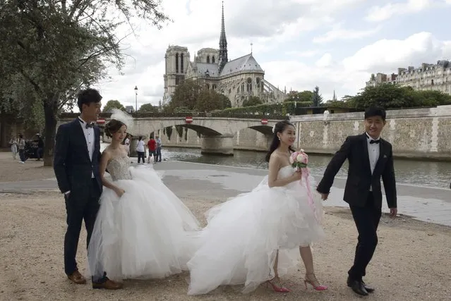 Two Chinese couples walk to attend their a pre-wedding photoshoots in front of the Notre-Dame Cathedral in Paris, France, August 28, 2015. (Photo by Philippe Wojazer/Reuters)
