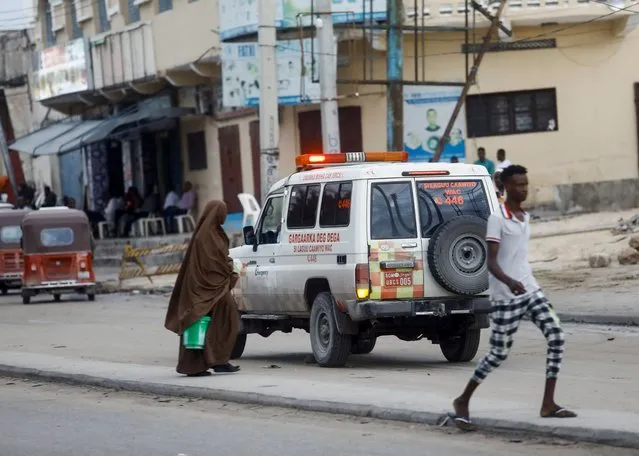People walk as an ambulance drives along a street near the scene of an al Qaeda-linked al Shabaab group militant attack at Hotel Hayat in Mogadishu, Somalia on August 20, 2022. (Photo by Feisal Omar/Reuters)
