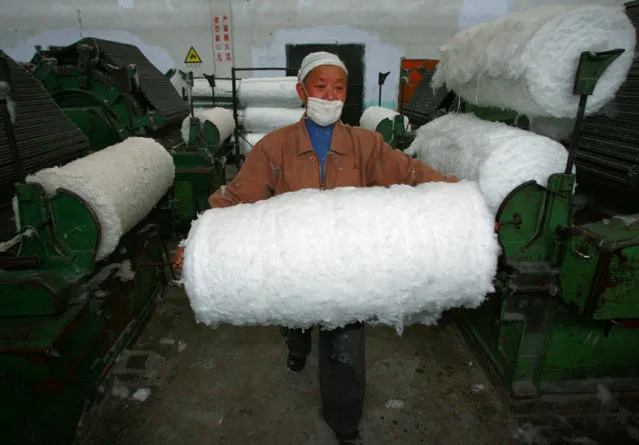 An employee carries a bale of cotton at the workshop of a textile factory in Suining, Sichuan province February 13, 2009. (Photo by Reuters/Stringer)
