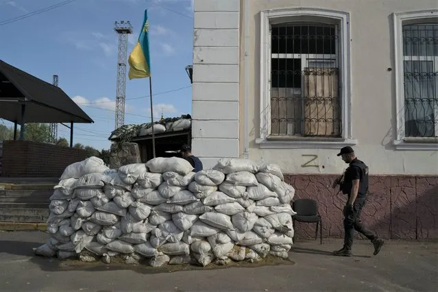 A member of the State Emergency Service of Ukraine enters in the basement of the train station fortified with sand bags that, according to Ukrainian authorities, was used as an interrogation room during the Russian occupation in the retaken village of Kozacha Lopan, Ukraine, Sunday, September 18, 2022. (Photo by Leo Correa/AP Photo)