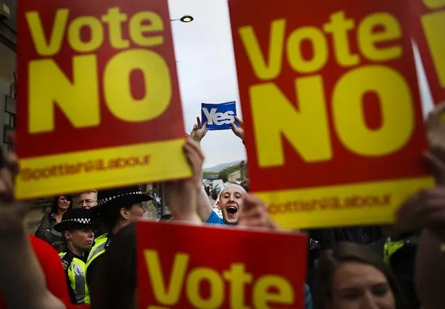 “Yes” campaigners and “No” supporters hold signs as former Prime Minister Gordon Brown leaves a rally in Glasgow, Scotland, on September 16, 2014. (Photo by Peter Macdiarmid/Getty Images)
