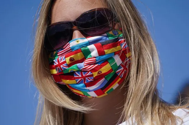 A protester wears a protective face mask with many nations' flags during a protest by travel agencies and tour bus operators during the coronavirus crisis on May 27, 2020 in Berlin, Germany. Approximately 300 tour buses took part in the protest and drove honking through the city center to demand government assistance due to heavy losses they are incurring during the pandemic. Similar protests took place in other cities in Germany today. (Photo by Sean Gallup/Getty Images)