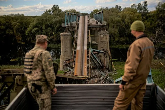 Ukrainian soldiers remove metal structure pieces as they work on a bridge damaged during fighting with Russian troops in Izium, Ukraine, Monday, October 3, 2022. (Photo by Francisco Seco/AP Photo)