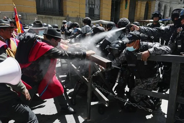Indigenous peasants from the Omasuyos province in the Bolivian highlands called the “Ponchos Rojos” (Red Ponchos), clash with riot police after marching from the city of El Alto to the government headquarters in La Paz, demanding the government fulfill promises for their sector, on October 5, 2022. The “Ponchos Rojos” are political allies of the ruling Movimiento Al Socialismo party. (Photo by Aizar Raldes/AFP Photo)
