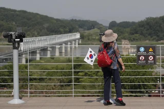 A visitor carrying a South Korean flag uses binoculars to view the northern side at the Imjingak Pavilion in Paju, South Korea, Tuesday, June 9, 2020. North Korea said Tuesday it will cut off all communication channels with South Korea as it escalates its pressure on the South for failing to stop activists from floating anti-Pyongyang leaflets across their tense border. (Photo by Lee Jin-man/AP Photo)