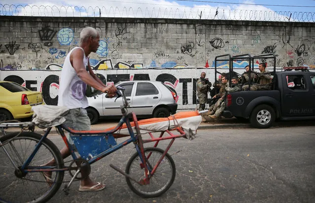 A man walks with a bike along the edge of the Mare “favela” community complex during an operation after National Force soldiers protecting Rio's Olympic Games were shot yesterday on August 11, 2016 in Rio de Janeiro, Brazil. Three soldiers were fired upon after taking a wrong turn into the complex with one being shot in the head. (Photo by Mario Tama/Getty Images,)