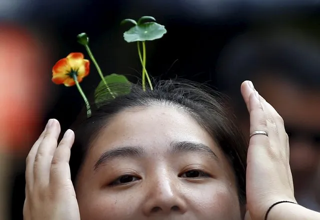 A woman wearing hairpins in the shape of sprouts and flowers makes her way on Nanluoguxiang street in Beijing, China, September 16, 2015. Wearing antenna styled hairpins in the shape of various flowers and plants at scenic spots has become a new trend in Beijing. (Photo by Kim Kyung-Hoon/Reuters)