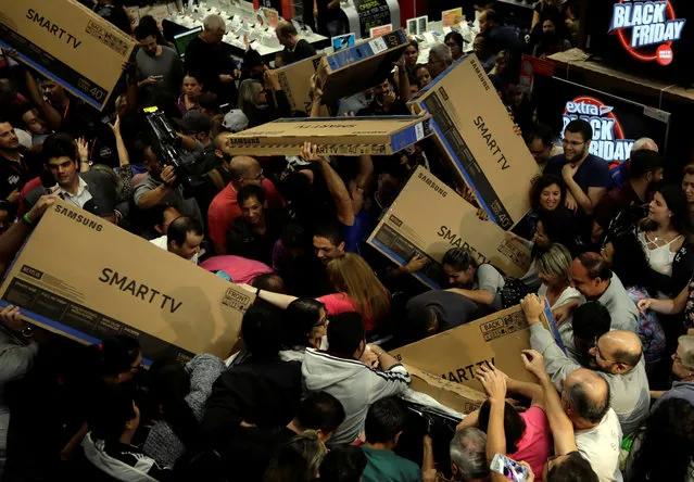 Shoppers reach out for television sets as they compete to purchase retail items on Black Friday at a store in Sao Paulo, Brazil on November 24, 2017. (Photo by Paulo Whitaker/Reuters)