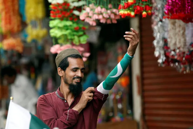 A man wears a national flag arm cuff while selling them at a stall on a roadside in Karachi, Pakistan July 24, 2016. (Photo by Akhtar Soomro/Reuters)