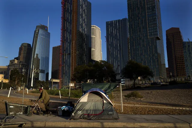 A homeless man, who declined to give his name, is dwarfed by skyscrapers Monday, December 4, 2017, in Los Angeles. The U.S. Department on Housing and Urban Development release of the 2017 homeless numbers are expected to show a dramatic increase in the number of people lacking shelter along the West Coast. (Photo by Jae C. Hong/AP Photo)