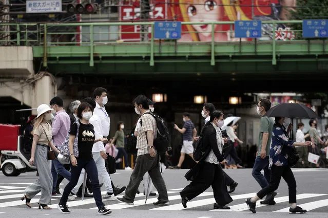 People wearing protective face masks to help curb the spread of the coronavirus walk at a pedestrian crossing Friday, July 10, 2020, in Tokyo. The Japanese capital has confirmed more than 240 new coronavirus infections on Friday, exceeding its previous record. (Photo by Eugene Hoshiko/AP Photo)