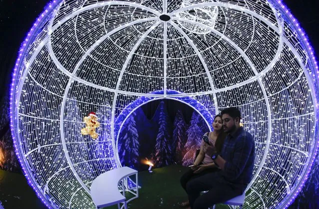 A fisheye lens image shows a couple seated inside a Christmas-themed light sculpture at the Gardens by the Bay in Singapore, 01 December 2017. The fourth edition of Christmas Wonderland, Singapore's biggest Christmas fair, will run from 01 to 26 December 2017 at the Gardens by the Bay. (Photo by Wallace Woon/EPA/EFE)