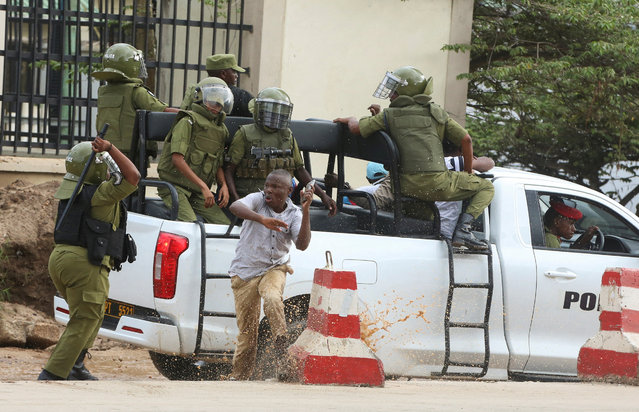 A Tanzania police officer attempts to detain a supporter of the opposition leader and former presidential candidate of CHADEMA party Tundu Lissu, as he runs from their pick-up truck, outside the Kisutu Residents Magistrate Court in Dar es Salaam, Tanzania on April 24, 2025. (Photo by Emmanuel Herman/Reuters)