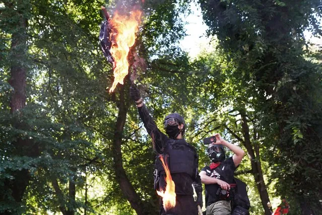 Anti-police protesters burn an American flag while facing off with right wing groups in front of the Multnomah County Justice Center on August 22, 2020 in Portland, Oregon. For the second Saturday in a row, right wing groups gathered in downtown Portland, sparking counter protests and violence. (Photo by Nathan Howard/Getty Images)