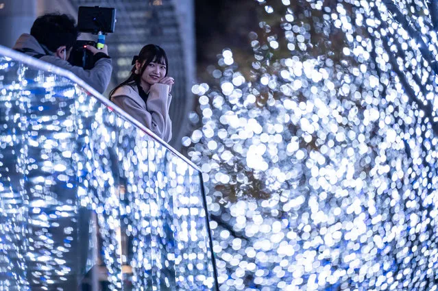 A woman has her photographs taken with illuminated trees in Tokyo on December 4, 2022. (Photo by Yuichi Yamazaki/AFP Photo)