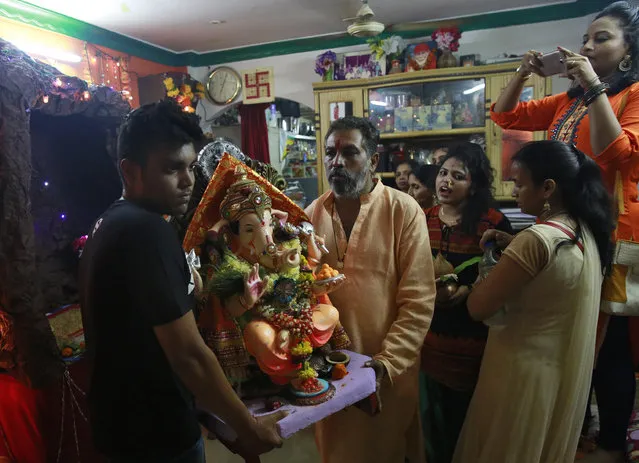 In this Tuesday, September 6, 2016 photo, Raju Laljibhai Dipikar and a relative carry an idol of elephant-headed Hindu god Ganesha to take it out of his house for immersion on the second day of Ganesha Chaturthi festival in Mumbai, India. (Photo by Rafiq Maqbool/AP Photo)