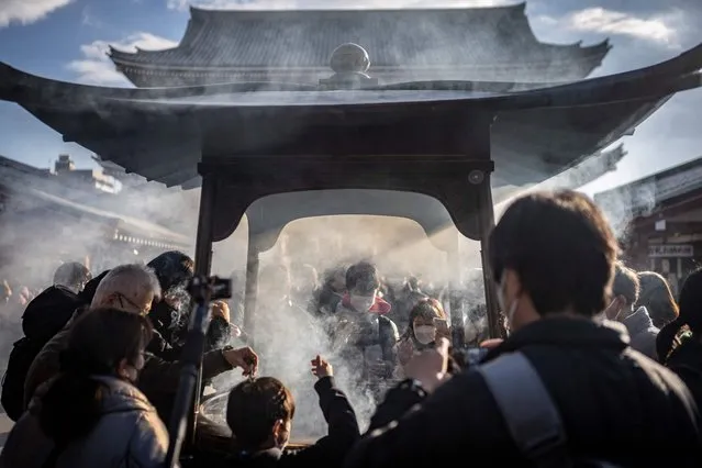 People pray around an incense burner at Sensoji temple ahead of the New Year holiday in Tokyo on December 30, 2022. (Photo by Yuichi Yamazaki/AFP Photo)