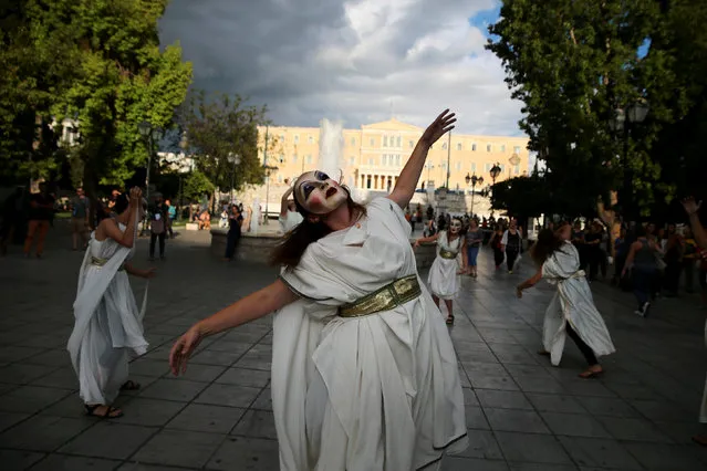 Women wearing ancient Greek costumes and masks dance during a performance, as the parliament building is seen in the background, in Athens, Greece, September 21, 2016. (Photo by Alkis Konstantinidis/Reuters)