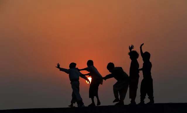 Pakistani children play on the roof of a house on the outskirts of Lahore on November 19, 2014. The United Nations' Universal Children's Day is celebrated annually on November 20 to promote worldwide fraternity and understanding between children. (Photo by Arif Ali/AFP Photo)