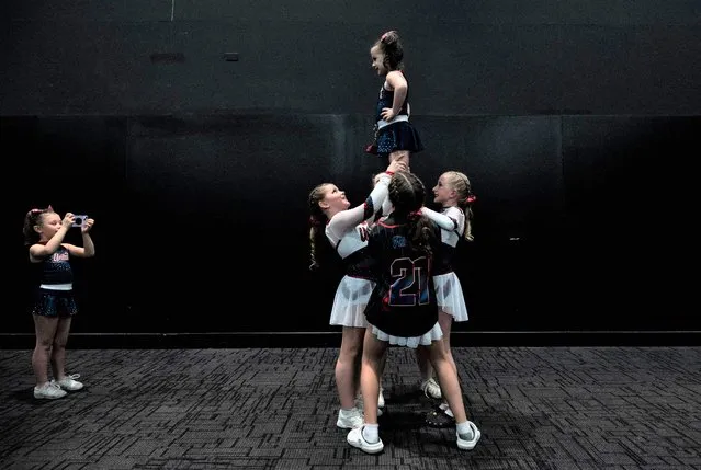 A young team member takes a photo of her teammates practicing during the Frost Extreme cheerleading event at the Chase Center in Wilmington, Delaware, on January 29, 2023. The event brings together recreational, high school, dance, and competitive teams to compete. (Photo by Andrew Caballero-Reynolds/AFP Photo)