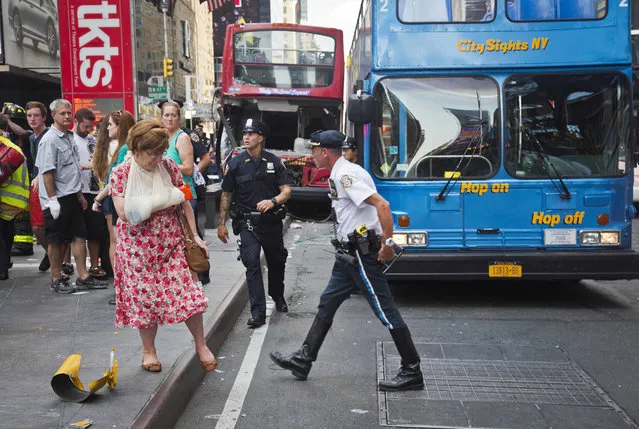 In this August 5, 2014, file photo, a woman leaves after being treated at the scene of a traffic accident involving two double-decker tour buses in New York's Times Square. On Monday, Dec. 4, 2017, Democratic state Sen. Brad Hoylman, of Manhattan, raised concerns about double-decker sightseeing buses in New York City, arguing tougher regulations are needed to protect tourists, pedestrians and other motorists. (Photo by Bebeto Matthews/AP Photo)