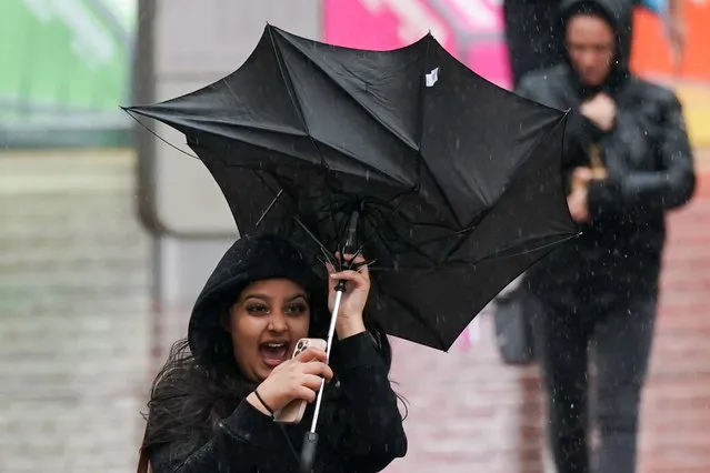 A woman struggles with her umbrella during the wet and windy weather in Birmingham, United Kingdom on Friday, September 30, 2022. (Photo by Jacob King/PA Images via Getty Images)