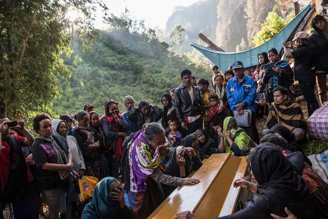Relatives cry as the coffin containing the bodies of Tikurara, Dumak and Limbongbuak arrived the Liang in Barrupu village, Toraja on August 22, 2016. The corpses were buried in Makassar a few years ago; this year the family decided to move the bodies to the stone grave in their hometown. But first, the family performed the Ma'Nene ritual. (Photo by Agung Parameswara/The Washington Post)