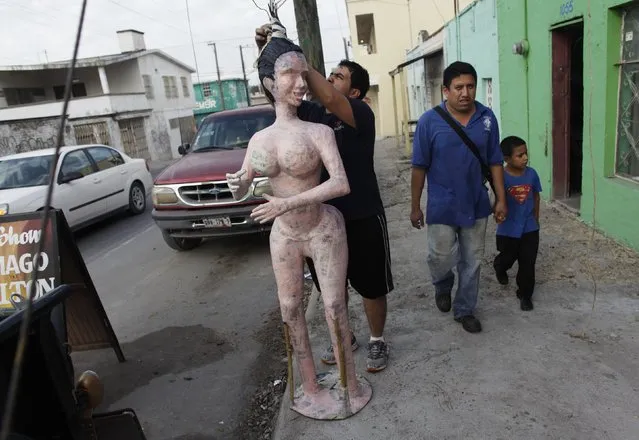 Mexican artisan Dalton Ramirez (partially covered by the pinata) works on a pinata depictingTV celebrity Kim Kardashian while standing outside his workshop in Reynosa December 6, 2014. (Photo by Daniel Becerril/Reuters)