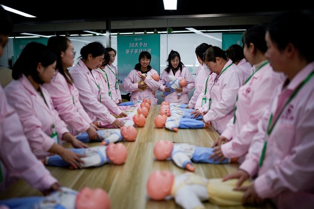 Women train with plastic baby dolls as they take part in a nursing skills class for confinement carers, at Yipeitong training centre in Shanghai, China on March 2, 2023. (Photo by Aly Song/Reuters)
