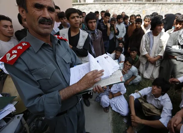 Afghan men wait as an official (L) holds their driving test papers at a traffic police department in Kabul August 23, 2014. (Photo by Mohammad Ismail/Reuters)