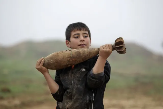 A boy carries a mortar shell left behind by forces loyal to Syria's President Bashar al-Assad at the Azaalana checkpoint, after rebels took control of two military posts from the forces, in the southern Idlib countryside December 20, 2014. (Photo by Khalil Ashawi/Reuters)