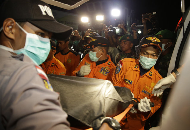 Officers of the National Search And Rescue Agency (BASARNAS) carry a victim's body of AirAsia flight QZ 8501 from a boat to an ambulance at  Kumai port in Pangkalan Bun, Indonesia, Wednesday, December 31, 2014. (Photo by Achmad Ibrahim/AP Photo)